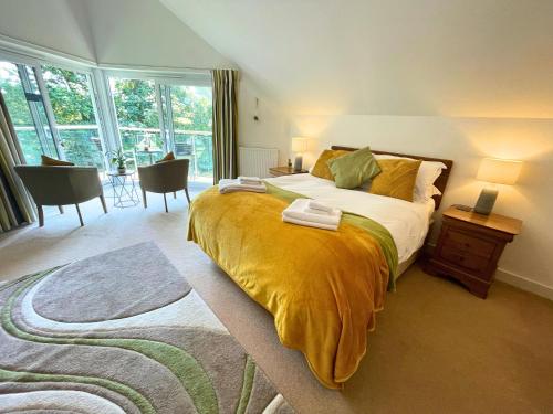 a bedroom with a large bed with a yellow blanket at Trewhiddle Retreat V12 by Together Travel - Luxury 4-Bedroom Villa in St Austell