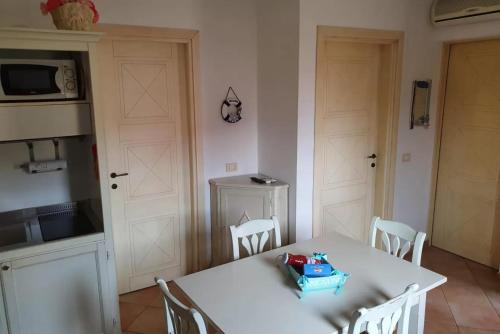 Vignola MareAffittaSardegna - Domo Vignola的厨房配有白色的桌椅和桌子,厨房