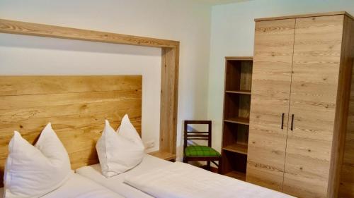 a bedroom with a white bed with a wooden headboard at Kurapotheke in Bad Hofgastein