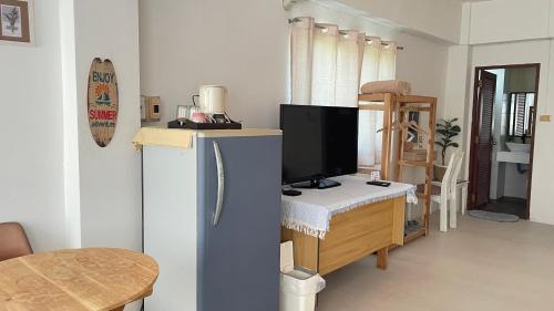 Una sala de estar con televisión y un escritorio con computadora. en A Day Rayong, en Ban Pa Khan