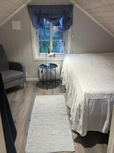 a bedroom with a bed and a chair and a window at Rosenli Gård in Tønsberg