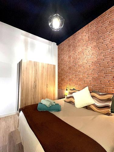 a bedroom with a large bed with a brick wall at Apartmento Ópalo in Seville