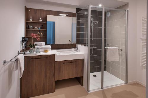 a bathroom with a glass shower and a sink at Domitys L'Orangerie in Sens