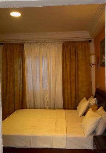 Sand Beach Holiday Resort في سيريكوندا: غرفة نوم بسرير مع شراشف بيضاء وستائر