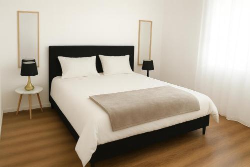 a bedroom with a large white bed with two lamps at La Grippiere in Petit-Bourg