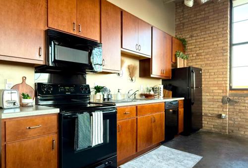 una cocina con electrodomésticos negros y armarios de madera en The Luxe Loft Boho Chic, en Duluth