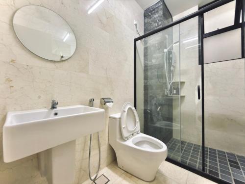 łazienka z toaletą, umywalką i lustrem w obiekcie The Cove Hillside Residence Ipoh by PLY Home w mieście Ipoh