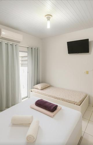 a white bedroom with a bed and a tv at ꕥ Cantinho da Margarida ꕥ Hospedagem & Hostel Premium - 03 Opções - SUÍTE Privativa, CAMAS Hostel ou Meia CASA - 1 Km do CENTRO de Belém, Hangar, UFPA, Turismo e Eventos - Máximo CONFORTO com Wi-Fi Ultra Rápido e Café da Manhã Grátis! - HOTEL Belém Pará in Belém