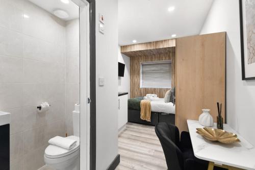 a bathroom with a toilet and a bedroom at Convenient Studio and Parking Easy Access Cntr London in Perivale
