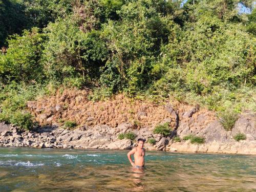 a man standing in the water in a river at Rickson Riverside Campsite in Dawki