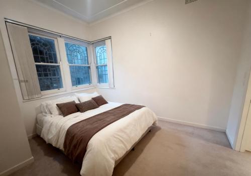 a white bedroom with a large bed and two windows at Quiet Guest Room in Burwood in Sydney