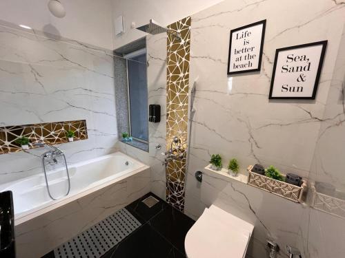 a white bathroom with a tub and a sink at Casa Oceanus - Pool View Room - Ganpatipule in Nevra
