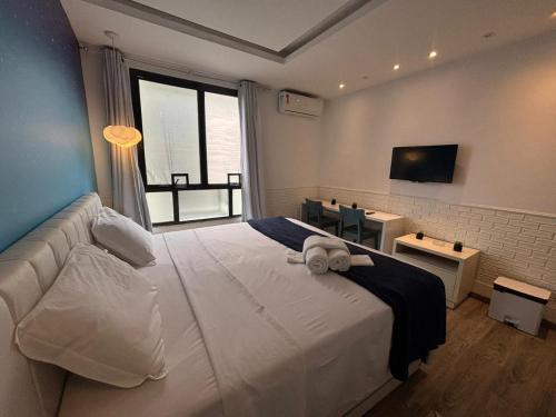 una camera da letto con un grande letto bianco e una finestra di Real Residence Hotel a Rio de Janeiro