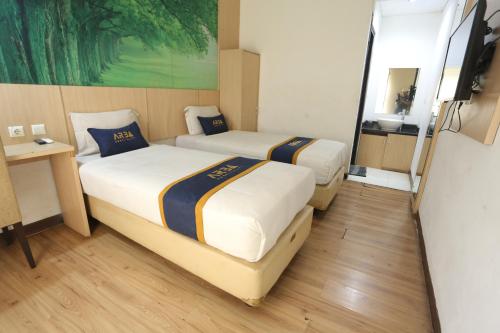 una camera d'albergo con due letti e uno specchio di King Stone Hotel By ARBA a Kranggan-wetan Satu