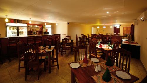 a restaurant with wooden tables and chairs and a bar at Mokoro Lodge in Maun