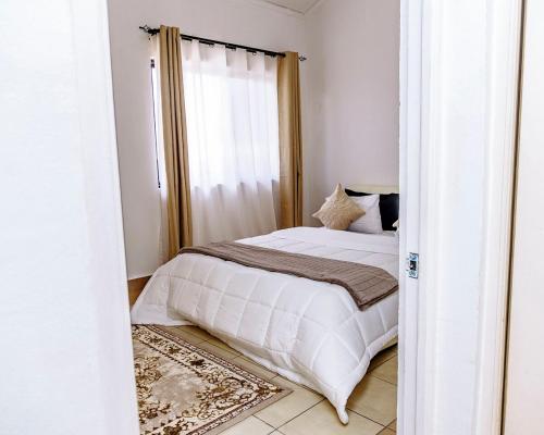 una camera da letto con un letto bianco e una finestra di Metris Foxdale Apartments a Lusaka