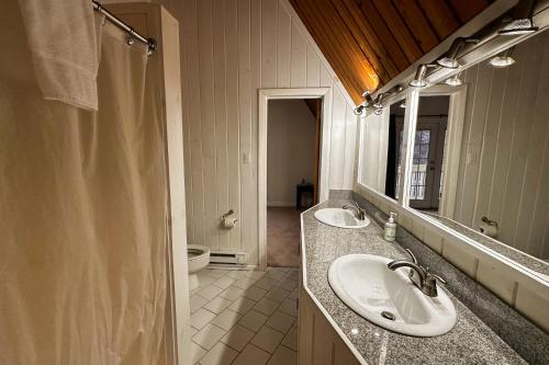 a bathroom with two sinks and a mirror and a toilet at Middle Pines Chalet in Warren