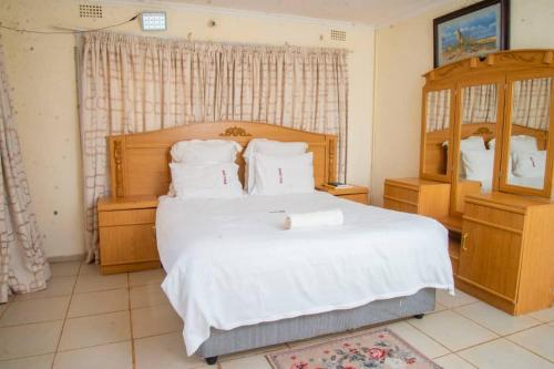 卢萨卡mck lodge ltd的卧室里有一张白色的大床和一面镜子