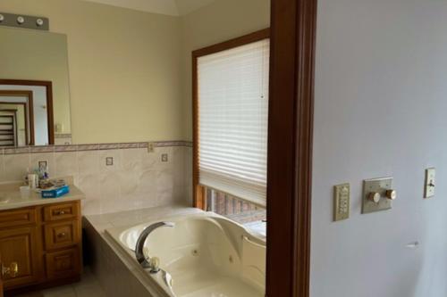 een badkamer met een bad, een wastafel en een spiegel bij La Casa De La Playa in Lanesville