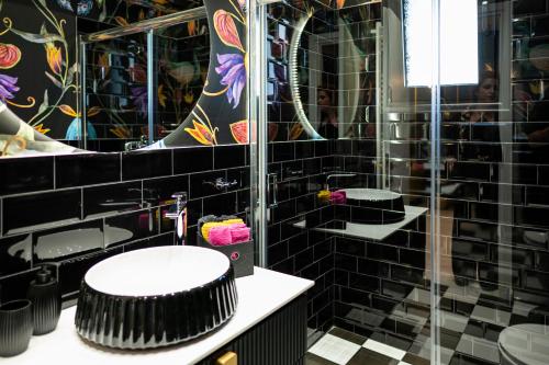a black tiled bathroom with a toilet and a mirror at The Loft Life in Tríkala