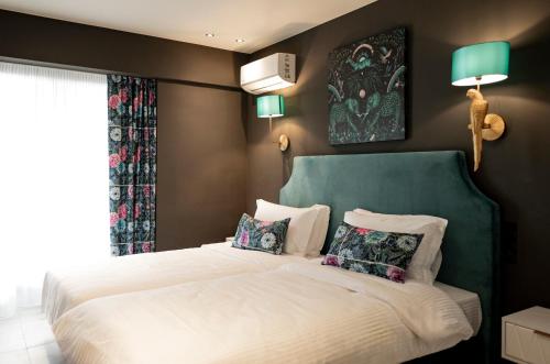 a bedroom with a bed with a green headboard and pillows at The Loft Life in Tríkala