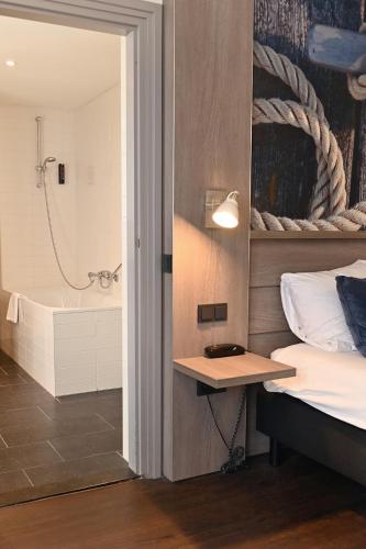 ein Schlafzimmer mit Bett und ein Badezimmer mit Dusche in der Unterkunft Hotel Medemblik in Medemblik