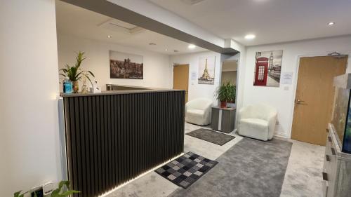 a lobby with a counter and two chairs in a room at Heathrow Travellers Hub in Hounslow