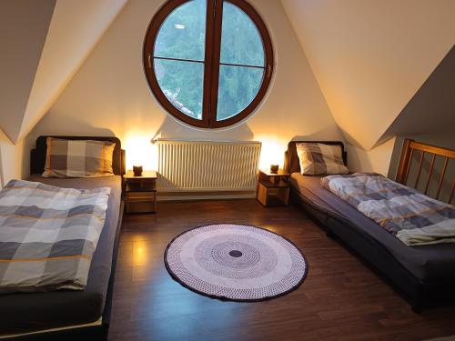 a attic room with two beds and a large window at Apartmán 19 MEZONET in Jáchymov