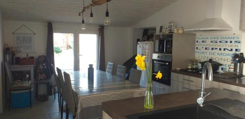a kitchen with a table with yellow flowers in a vase at Maison 6 personnes in Barbâtre