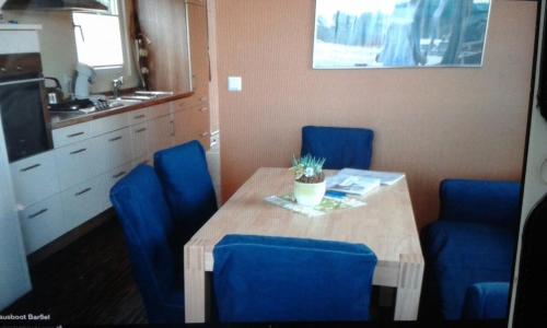tavolo da pranzo con sedie blu e cucina di Hausboot Levitate im Hafen von Barßel a Barßel