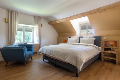 a bedroom with a large bed and a blue chair at Auberge du chateau de Leignon in Leignon
