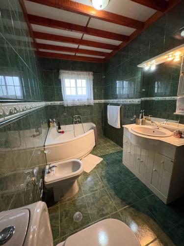 a bathroom with two sinks and a tub and a toilet at Zizi home in Biscoitos