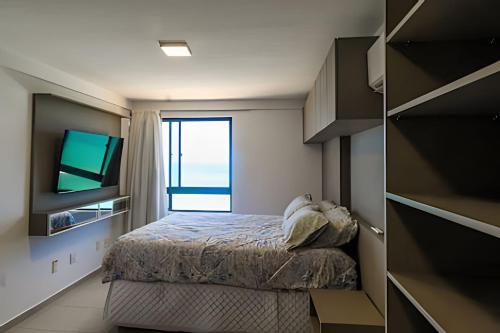 ein kleines Schlafzimmer mit einem Bett und einem Fernseher in der Unterkunft Cobertura duplex de frente pro mar in Natal