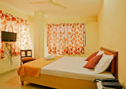 a bedroom with a bed with an orange blanket and a window at All Seasons Guest House in Trivandrum