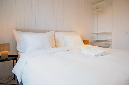 una cama blanca con sábanas y almohadas blancas en Lakefront Grand Residence, en Ligerz