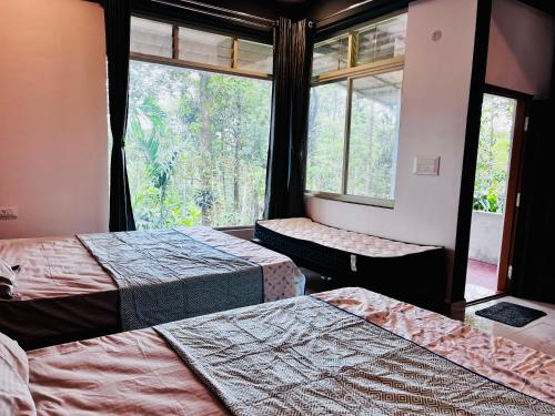 Cette chambre comprend deux lits et une grande fenêtre. dans l'établissement greenSpun nature Stay, à Somvārpet
