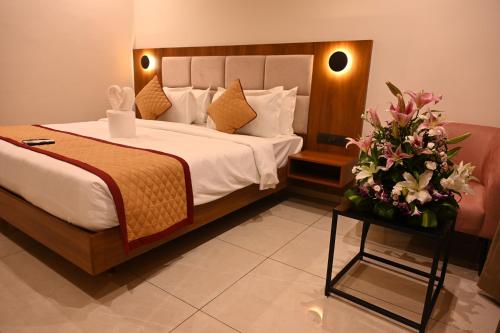 a bedroom with a bed and flowers on a table at Good One Suites Near Manyata Tech Park in Bangalore