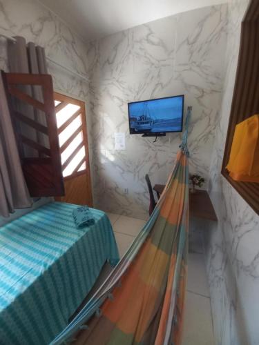 a bedroom with a bed and a tv on a wall at Aracaju Suite - Wi-Fi, Ar e Ótima Localização in Aracaju