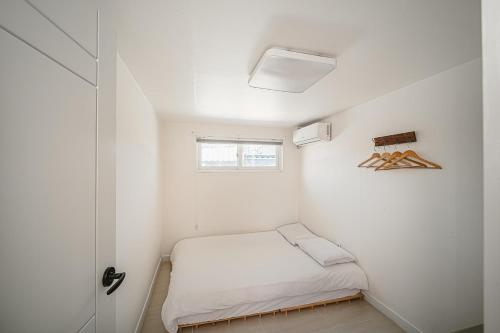 a small white room with a bed and a window at 신흥부부공간a동 in Hamdŏng-ni