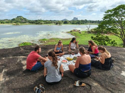 a group of people sitting on a rock eating food at Sigiri Lake Paradise in Sigiriya