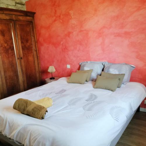 un grande letto bianco in una stanza con una parete rossa di Maison Pucet a Pey