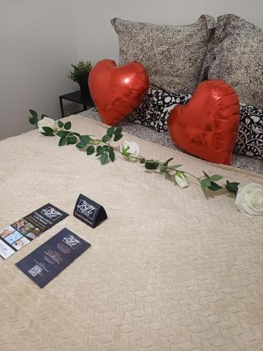 Love Room - Spa Privatif Gard في Saint-Michel-d'Euzet: سرير عليه قلبان أحمران وزهور