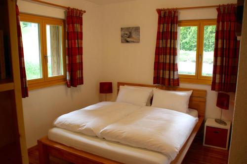 a bed in a bedroom with two windows at Chesery 8 in Morgins