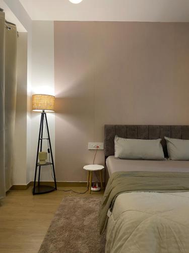 a bedroom with a bed and a lamp and a table at Flat in Viman Nagar in Pune