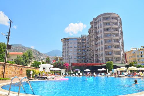 a large swimming pool with people in a hotel at Club Sidar Apart Hotel in Alanya