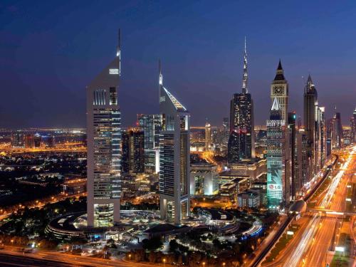 a city skyline at night with a clock tower at Swissôtel Al Murooj Dubai in Dubai