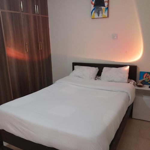 a bedroom with a large bed with white sheets at Swali residence in Nakuru