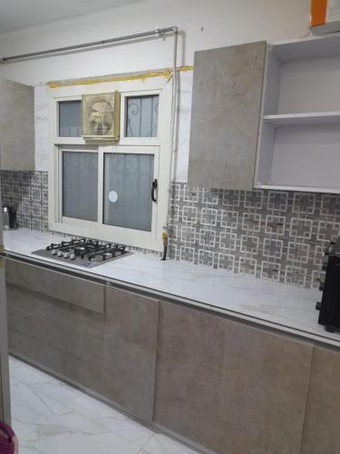 uma cozinha com fogão e janela em عمارات ميلسا سيتى ستارز em Banī Ghālib