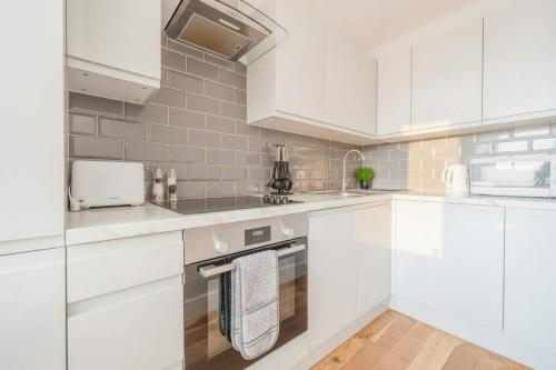 a white kitchen with white counters and white cabinets at Fabulous Central Eastleigh 1 Bedroom Apartment in Eastleigh