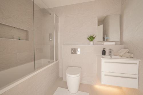 a white bathroom with a toilet and a sink at Fabulous Central Eastleigh 1 Bedroom Apartment in Eastleigh